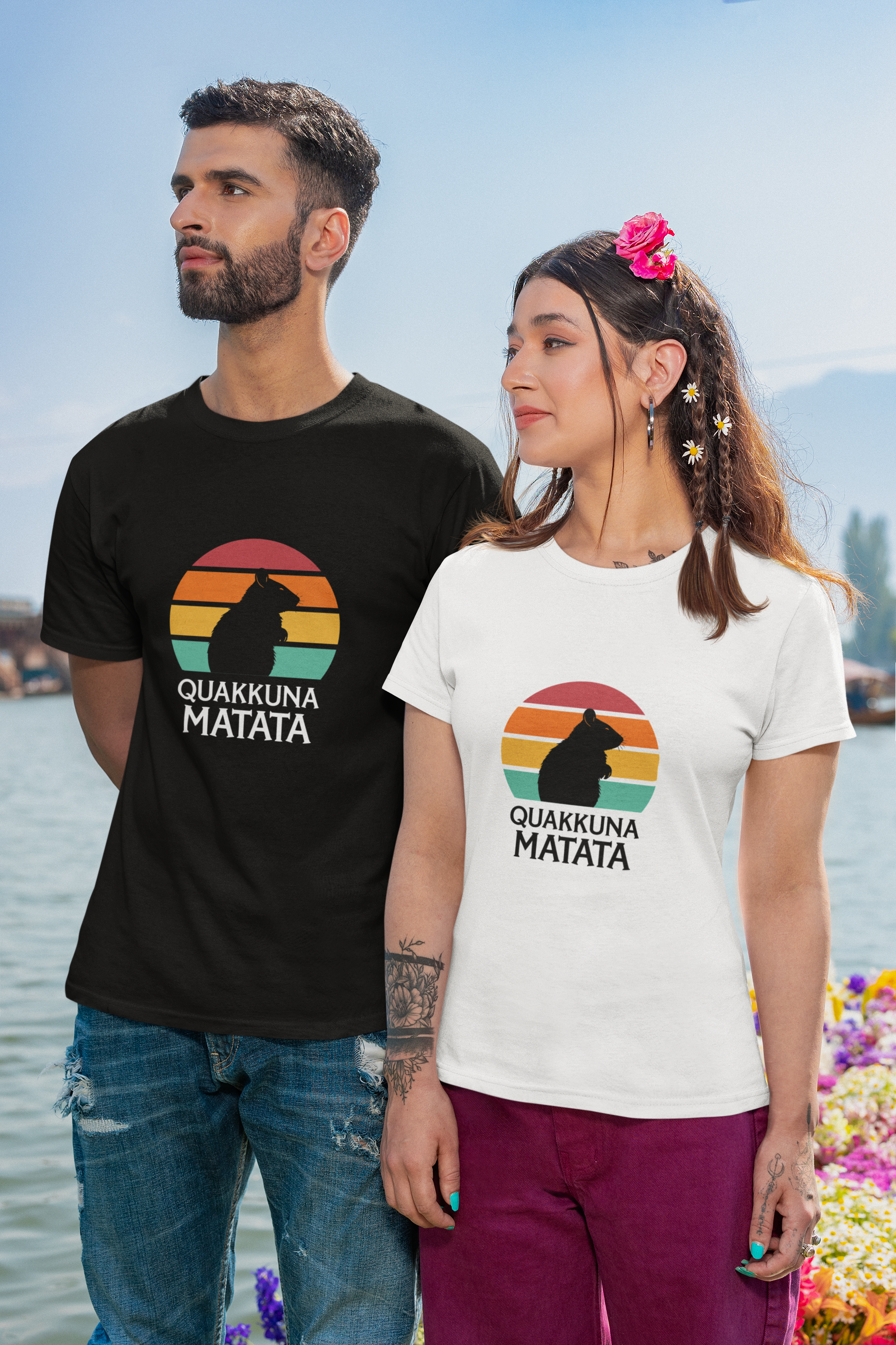 Couple wearing matching Quakkuna Matata T-shirts, inspired by Disney's Hakuna Matata from The Lion King. The man wears black, and the woman wears white, both with a retro sunset and quokka silhouette design.