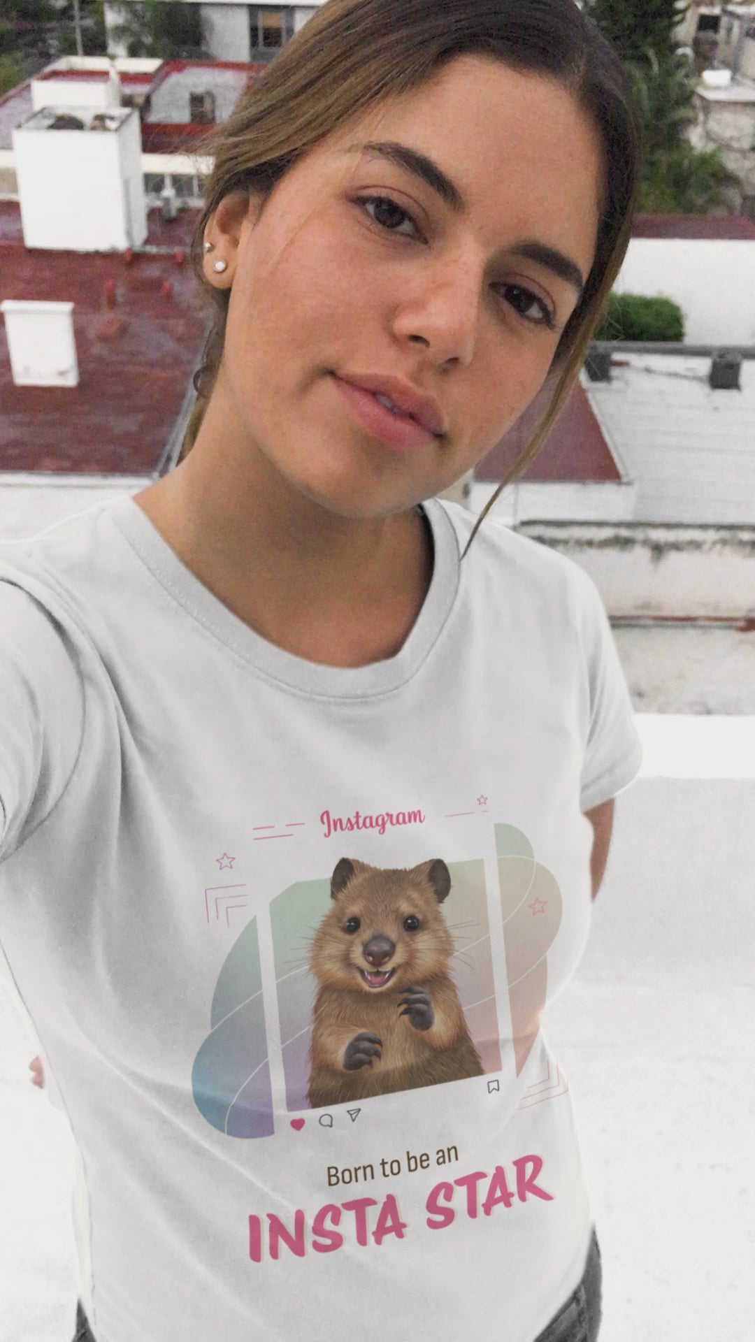 Selfie video of a young woman wearing a white T-shirt with a quokka Instagram design and 'Born to be an Insta Star' text. Capturing a vibrant and stylish social media look.